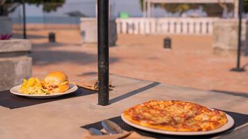 Uma mesa com pizza, um hambúrguer, um guardanapo e um garfo.