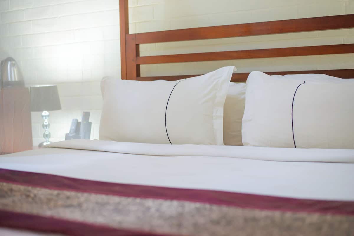 A neatly made bed with white linens and a wooden headboard.