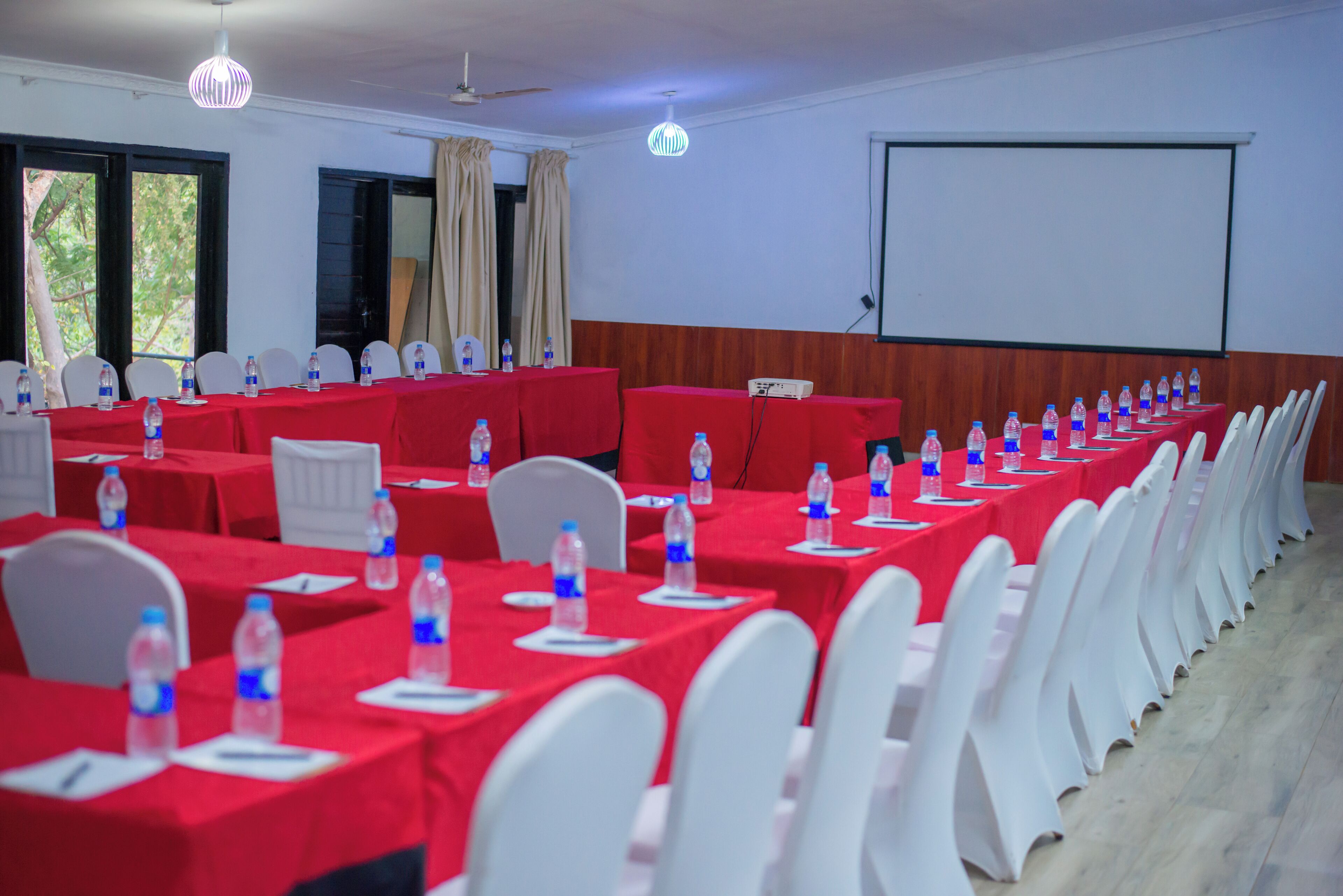 A conference room with rows of tables, chairs, and water bottles.