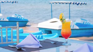 A table with a drink, a napkin, and a fork, set against a backdrop of boats and water.