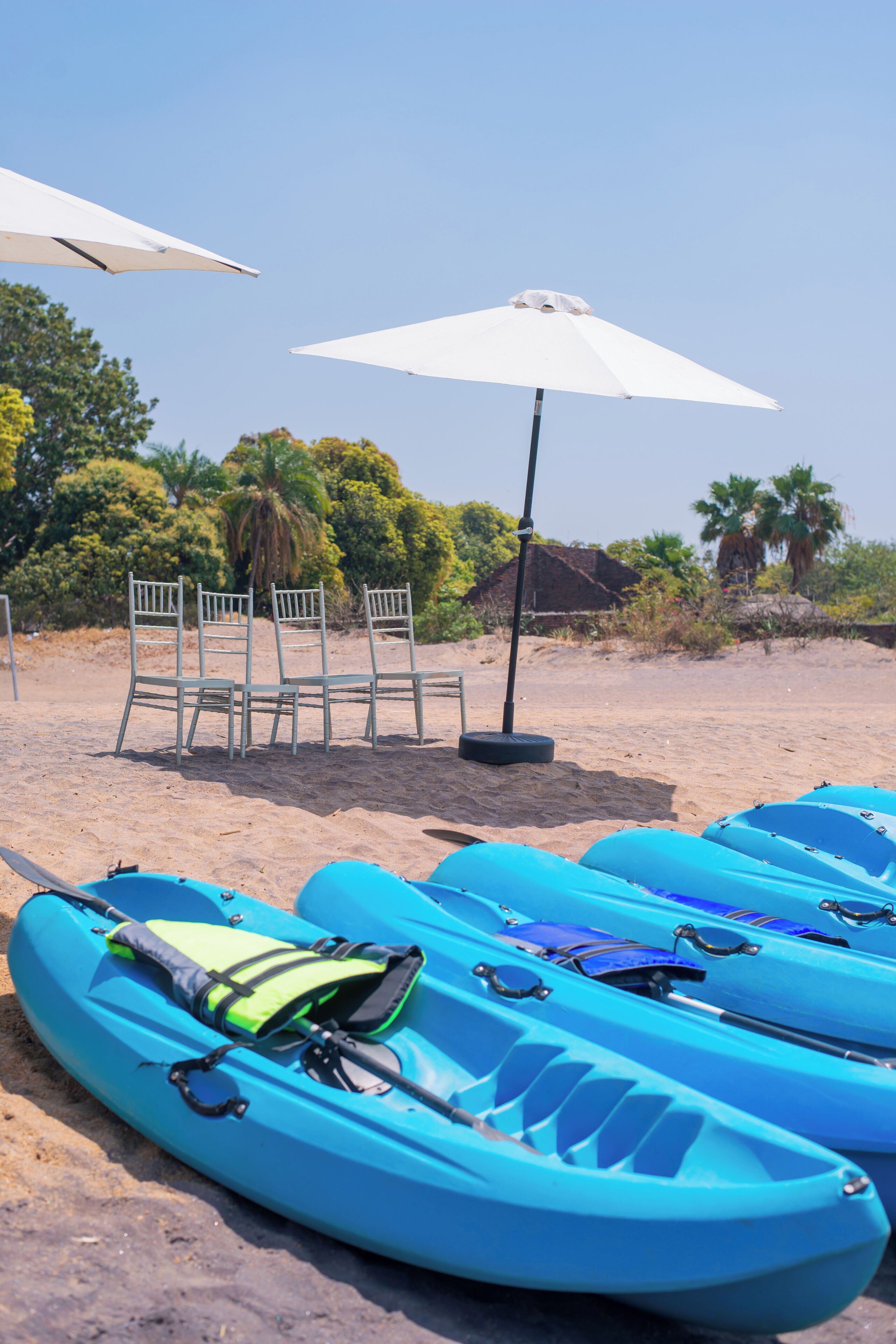 A beach with kayaks, chairs, and umbrellas.