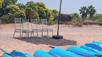 A beach with kayaks, chairs, and umbrellas.
