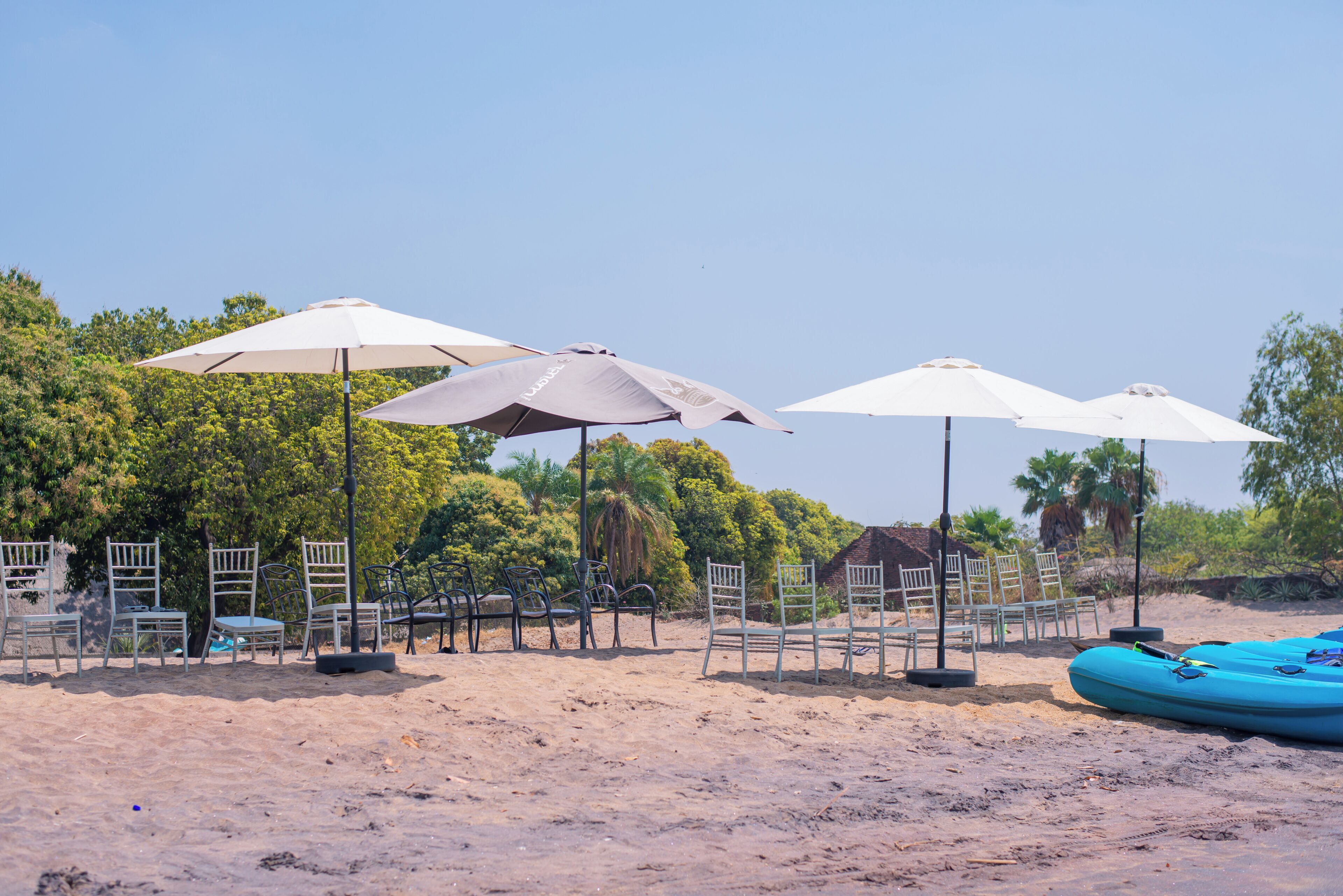 A beach with umbrellas, chairs, and a blue raft.