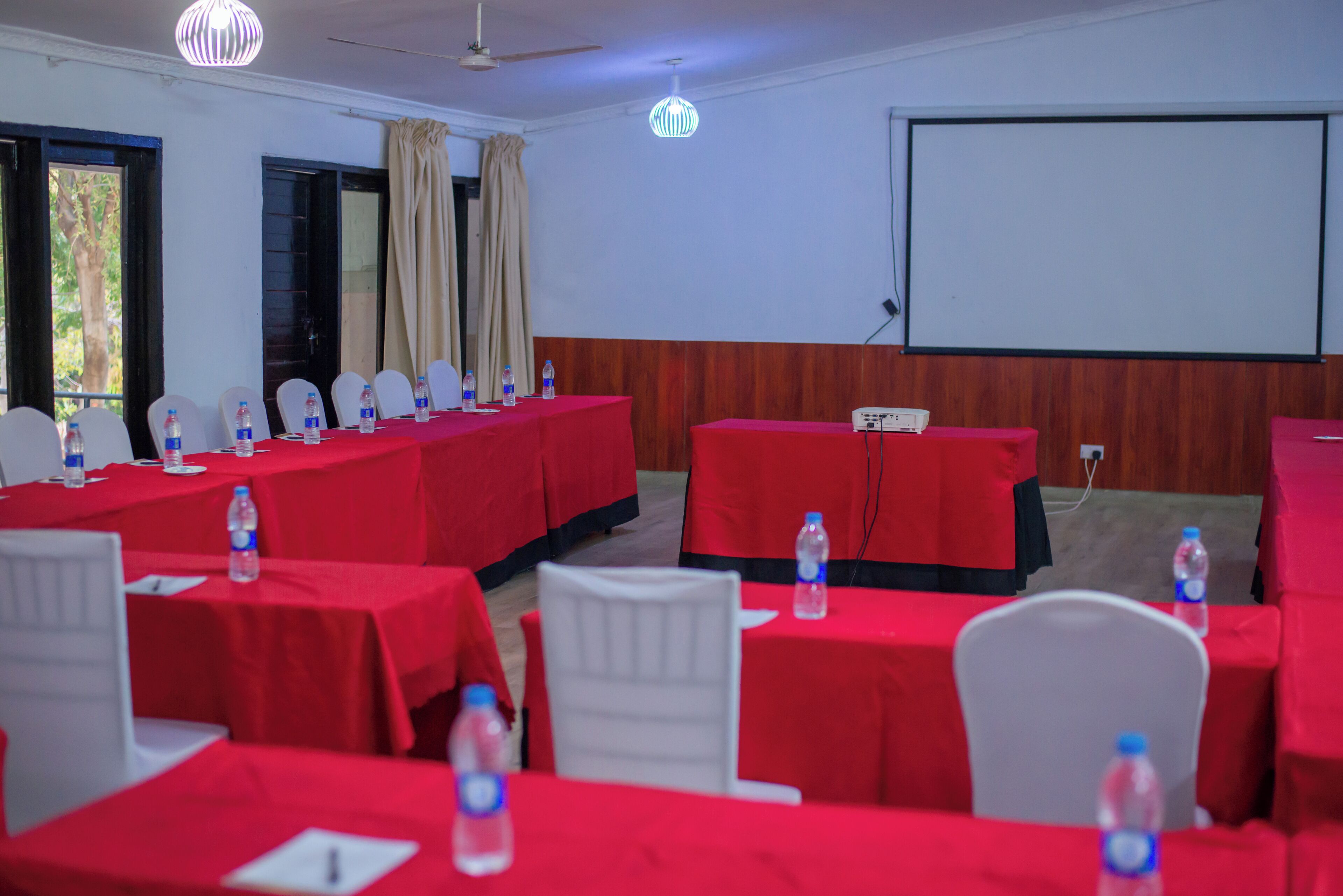 A conference room with red tables, white chairs, and water bottles.