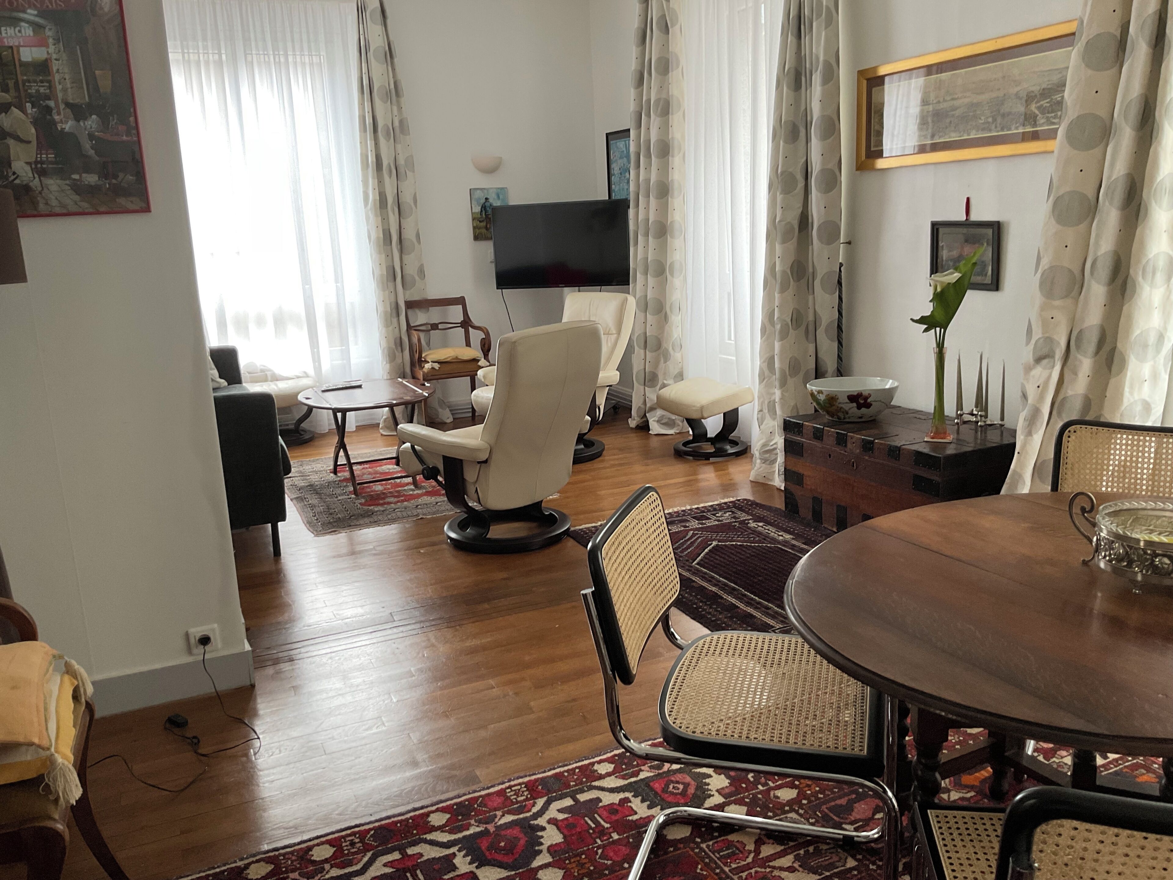 Ein Wohnzimmer mit Holzboden, einem Esstisch, einem Fernseher und einem Sofa.