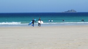 A beach with people walking and surfing. - Little Pengelly Farm (Hayle)