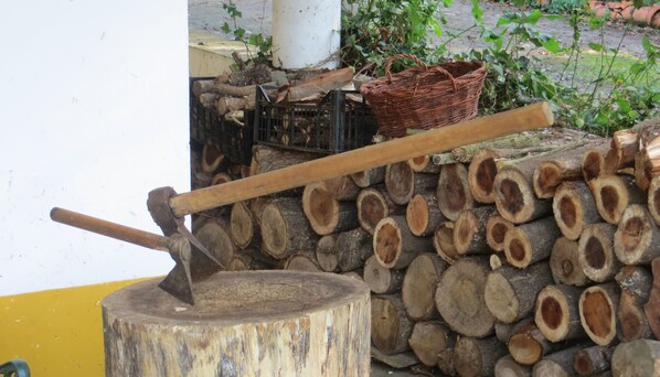 A wooden log stack with a metal tool and a woven basket on top.