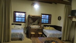 Une pièce avec deux lits, une table en bois et une petite structure en bois dotée d’une fenêtre.