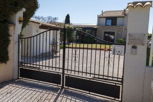 Uma entrada com portão fechado, parede de pedra e grade de metal.