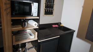 A compact kitchen with a microwave, kettle, and various kitchen utensils on shelves. - La chambre des Onglous (Marseillan)