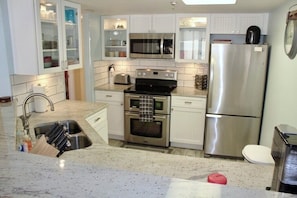 A kitchen with white cabinets, stainless steel appliances, a sink, and a microwave.