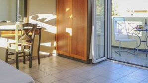 Ein Zimmer mit Esstisch, einem Holzschrank, einem Stuhl und einer Glastür, die zu einem Außenbereich mit Tisch und Stühlen führt.