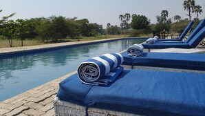 Zona de piscina con sillones de descanso y toallas.