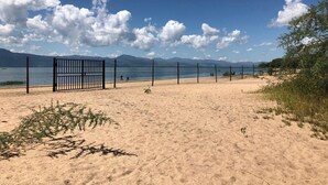 Una playa con una valla y montañas al fondo.