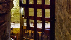 Un arco de piedra conduce a un comedor con sillas y una mesa de madera dispuesta para dos personas.