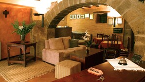 Un interior acogedor con un arco de piedra que da a un comedor, un sofá y una mesa de madera con un florero.