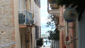Un callejón estrecho entre edificios con balcones, algunos con barandillas y macetas.