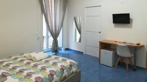 Un dormitorio con una cama, un escritorio, una silla, un televisor y un mueble bajo.