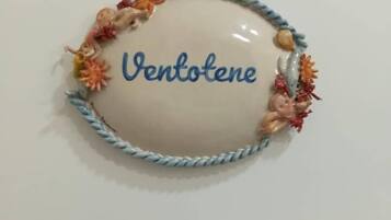 A white table with a decorative item featuring the name "Ventotene" and a braided border with colorful beads.