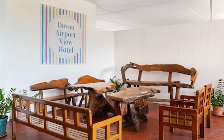 A room with rustic wooden furniture, including a bench and chairs, and a sign on the wall that reads "Davao Airport View Hotel".