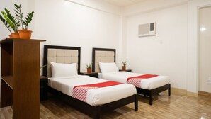 A hotel room with two beds, a wooden wardrobe, and a potted plant. - Davao Airport View Hotel (Davao)