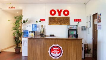A reception desk with a '100% Fully Controlled by OYO' sticker, a 'NO SMOKING' sign, and a water dispenser.