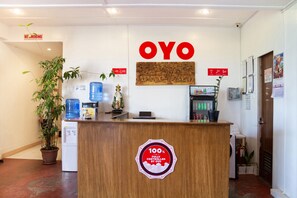 A reception desk with a '100% Fully Controlled by OYO' sticker, a 'NO SMOKING' sign, and a water dispenser.