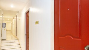 A hallway with a red door, a water dispenser, and a sign indicating an exit. - Davao Airport View Hotel (Davao)