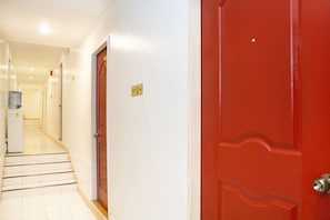 A hallway with a red door, a water dispenser, and a sign indicating an exit. - Davao Airport View Hotel (Davao)