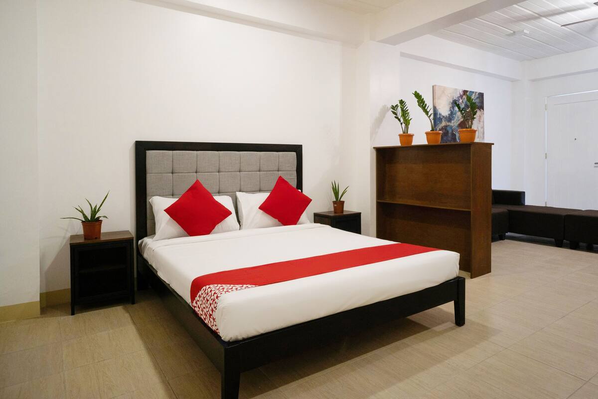 Une chambre à coucher bien rangée, avec un lit, deux tables de chevet et un banc en bois.