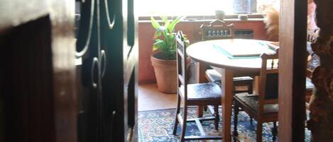 An open doorway leading to a dining area with a table and chairs, a potted plant, and a window with a view of the outside.