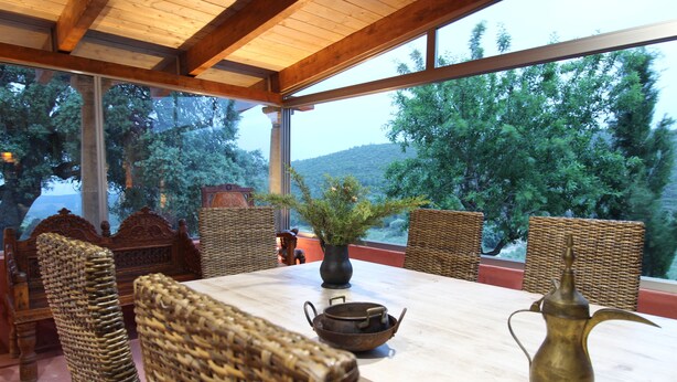 A dining area with wicker chairs, a table, a vase, and a teapot. - Masia Heredad La Boquilla (Enguera)
