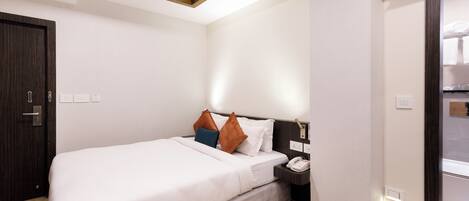 Una habitación de hotel con cama, mesita de noche y aire acondicionado.