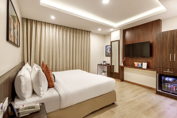 A hotel room with a large bed, a flat-screen TV, wooden cabinets, and a minibar. - Hotel Sabrina Kathmandu (Burhanilkantha)