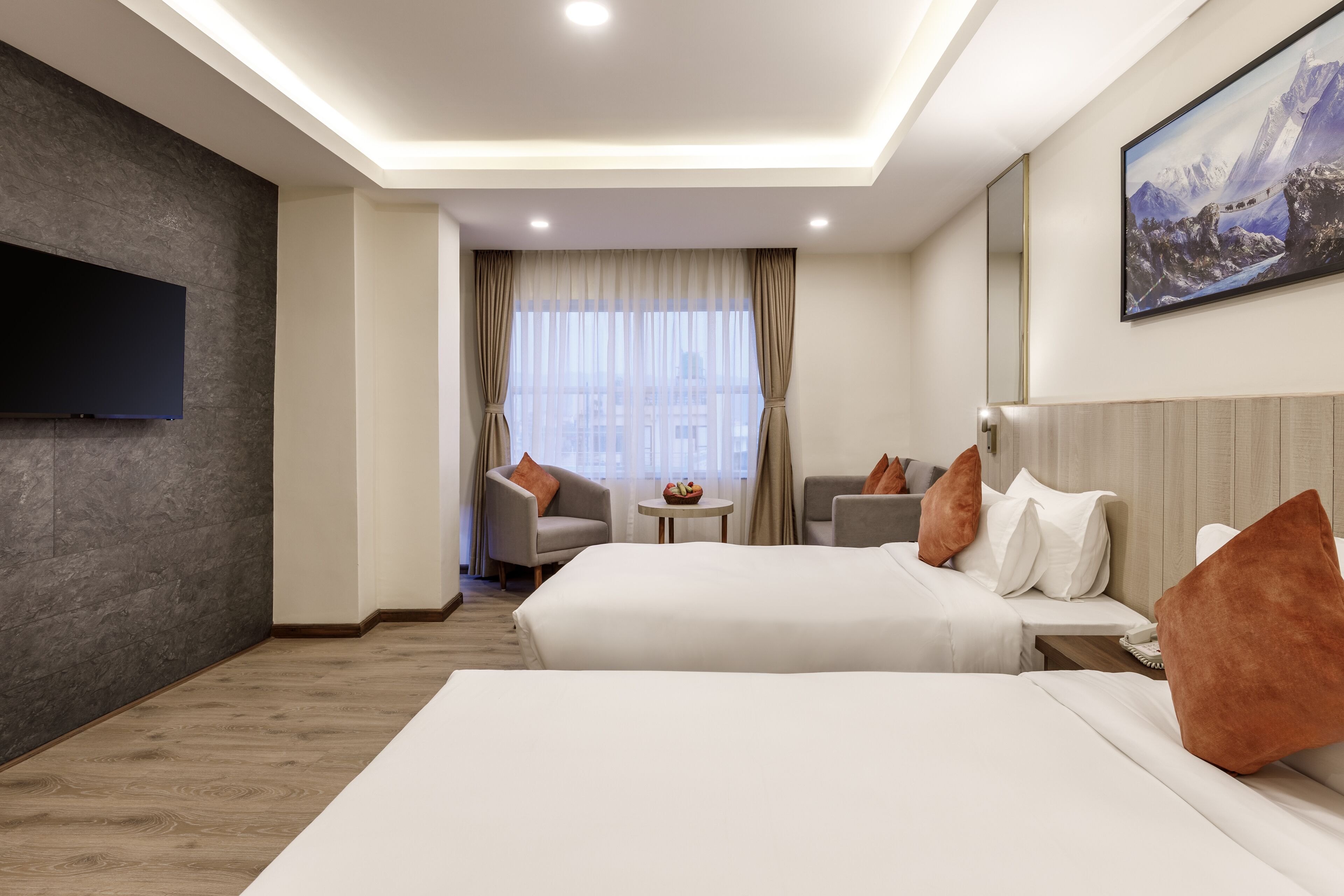 A hotel room with two beds, a TV, a painting, and a view of the city through the window.