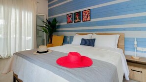 Une chambre d’hôtel avec un lit, une table de chevet, une lampe de chevet, une plante en pot et une fenêtre avec des rideaux.