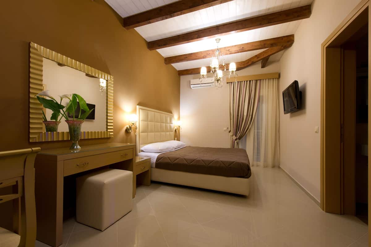 Un dormitorio con cama, escritorio, tocador, espejo, candelabro y televisor.