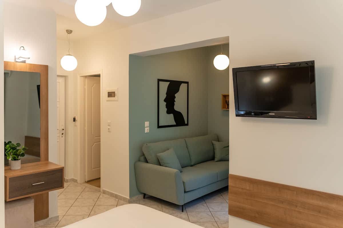 Una sala de estar moderna con un sofá, un televisor de pantalla plana montado en la pared, una consola de madera con un espejo y una planta.
