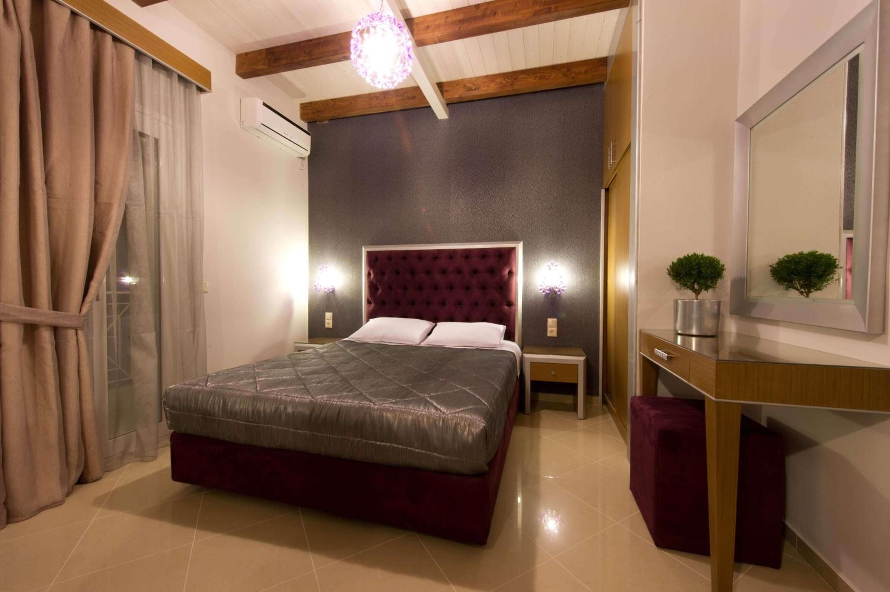 A bedroom with a large bed, a bedside table, a nightstand, a mirror, and a small potted plant.