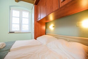 A bedroom with a bed, a window, and wooden cabinets.