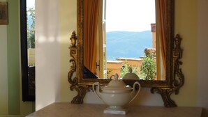 A room with a large ornate mirror reflecting a view of mountains and a balcony with plants. - Dimora Garibaldi (Castelnuovo Magra)