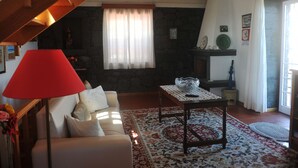 Un salon chaleureux avec un canapé, une lampe rouge, une cheminée et un mur en pierre.