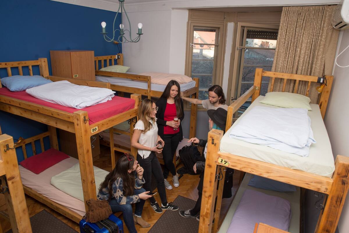 A dormitory room with bunk beds, a wooden wardrobe, and a chandelier.