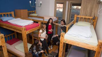 A dormitory room with bunk beds, a wooden wardrobe, and a chandelier.