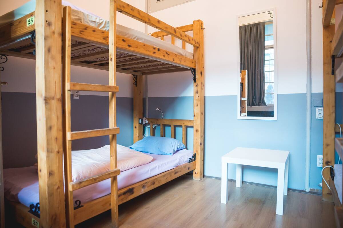 A bunk bed room with a small table and a window with curtains.