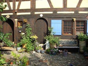 A traditional half-timbered building with a courtyard filled with potted plants and a bench.