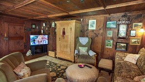 Una sala de estar acogedora con paredes de madera, un televisor, un mueble de madera y un sofá estampado.