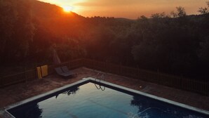 Piscina retangular com escada de metal, rodeada por um pátio de tijolos.