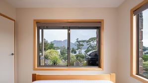 A bedroom with a large window, a bed, and a view of mountains and trees. - Greystone (FS5) - Freycinet Holiday Houses (Coles Bay)