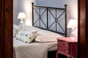A bed with a black metal headboard, white bedding, and two bedside lamps.